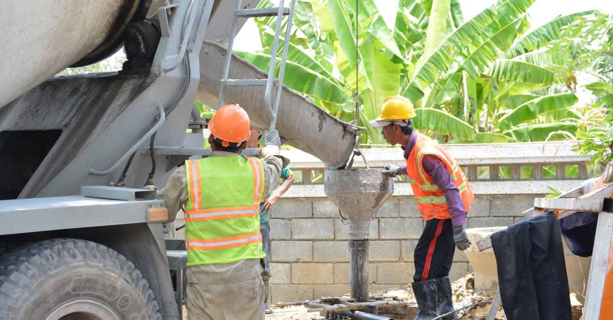 Construction team pouring concrete on site with mixer truck, enhancing a sturdy foundation.
